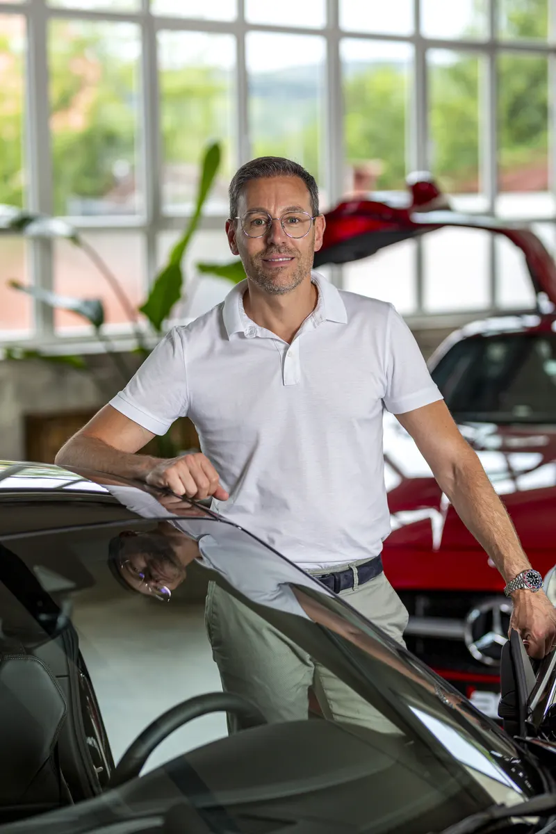 Alexander Schreck, Geschäftsführer der AS Handel GmbH, im Showroom vor einem roten Mercedes-Benz SLS AMG