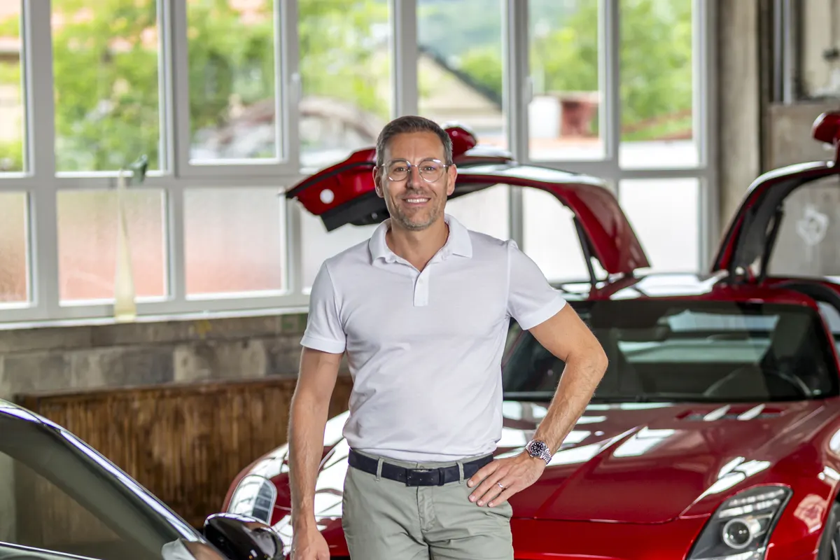 Geschäftsführer Alexander Schreck im Showroom vor einem roten Mercedes-Benz SLS AMG mit geöffneten Flügeltüren